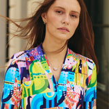 Kobieta w kolorowej, artystycznej sukience z geometrycznym wzorem, idealna na codzienne stylizacje i self-care fashion